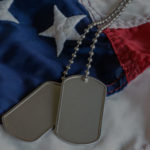 Va Benefits For Spouses military dog tags on American flag with embroidered stars
