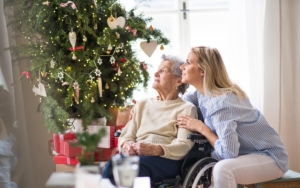 A home caretaker and elderly woman sitting by holiday decorations