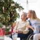 A home caretaker and elderly woman sitting by holiday decorations