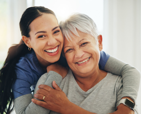 Front view of an elder and caregiver hugging