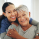 Front view of an elder and caregiver hugging