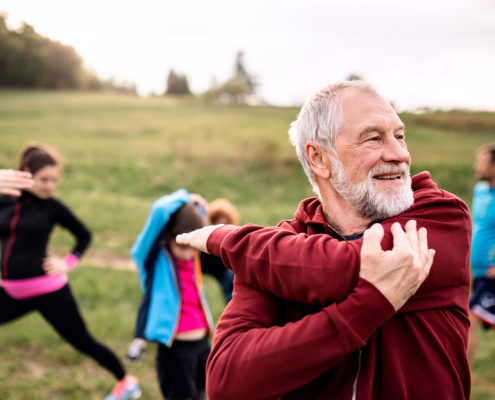 Large group of fit and active people doing exercise in nature, stretching