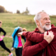 Large group of fit and active people doing exercise in nature, stretching